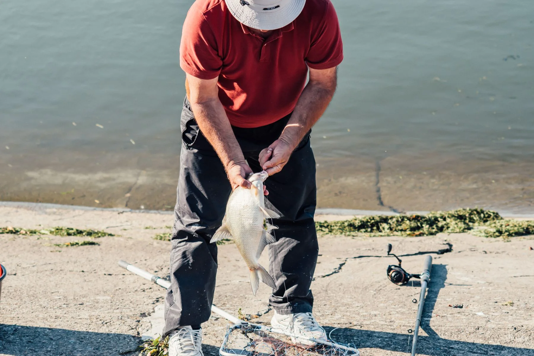 An angler holding a freshly caught fish beside the river.